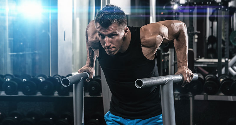 man doing dips on metal bars